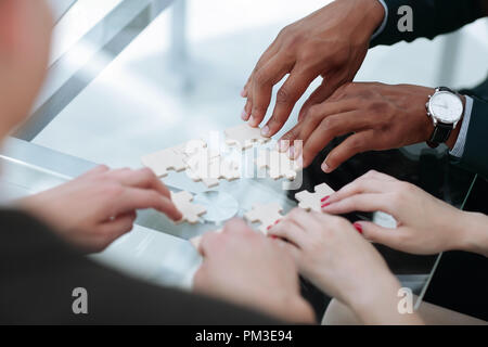 Close up. team aziende assemblaggio di pezzi di un puzzle. Foto Stock