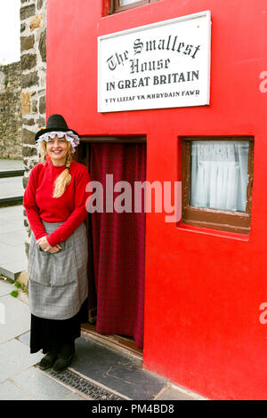 Conwy, donna nel periodo tradizionale costume gallese, sta in piedi in ingresso alla casa più piccola in Gran Bretagna, Wales, Regno Unito Foto Stock