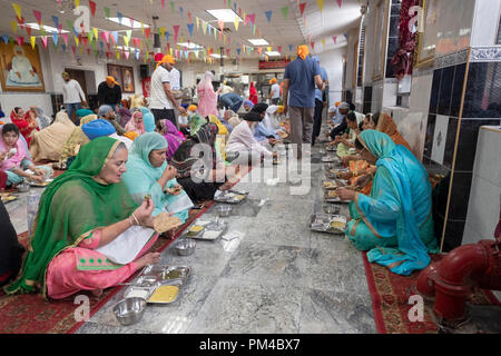 Donne e alcuni uomini di mangiare in un tempio sikh langar dove gratuitamente un pasto vegetariano è servita a chiunque senza eccezione. Foto Stock