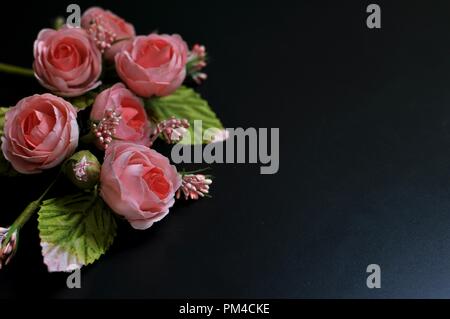 Artificial bouquet di rose rosa su sfondo nero con copia spazio. Vista frontale Foto Stock