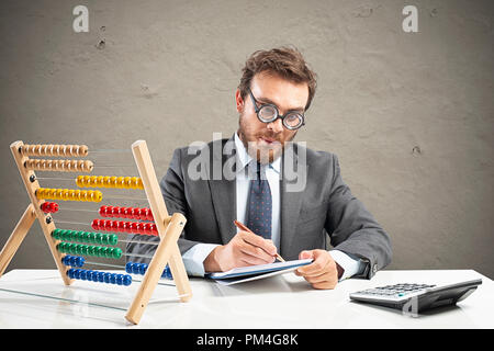 Nerd ragioniere fa il calcolo delle entrate di un'azienda Foto Stock
