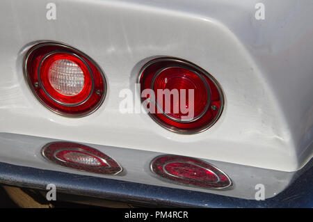 Due round di coda che riflette la luce da chrome paraurti posteriore di un classico bianco auto. Foto Stock