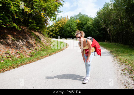 Donna di viaggiatori stanchi e fanno male le gambe da ha perso il suo titolo nella foresta in estate Foto Stock