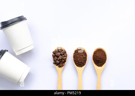 Cucchiai di legno riempito di caffè in grani frantumati e caffè macinato , carta tazza di caffè e di parola su sfondo bianco Foto Stock