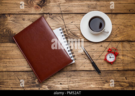 Diario in custodia in pelle e la tazza di caffè su sfondo di legno. Istruzione e concetto di ufficio Foto Stock
