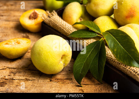 Pesche gialle su una tavola in legno rustico Foto Stock