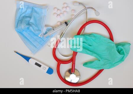 Il concetto di medicina Apparecchiature: medicina lo stetoscopio e pillole, siringa, guanto chirurgico, il termometro digitale su sfondo bianco. Cura di salute o di malattia. Foto Stock