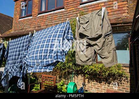 Verifica magliette e pantaloncini appeso al di fuori su una linea di lavaggio asciugatura in una giornata di vento Foto Stock