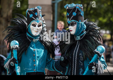Un uomo e una donna in turchese e nero costumi veneziani a piedi la strada durante il carnevale Foto Stock