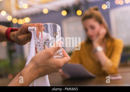 Barman professionali tiene il vetro nelle sue mani durante la pulizia Foto Stock