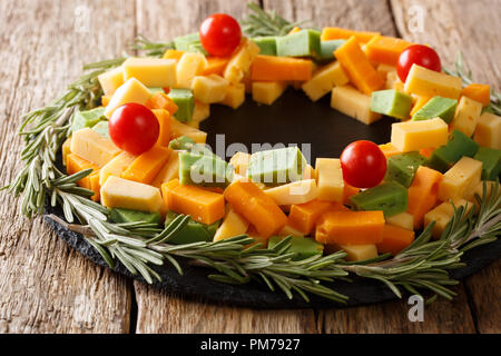 Pesto affettato, formaggio cheddar, Mimolette con pomodori e rosmarino vicino sul tavolo. Decorazioni di Natale. orizzontale Foto Stock