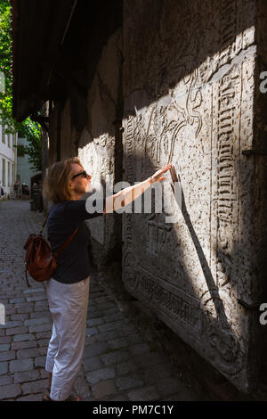 La donna viaggia da sola e osserva una donna matura che tocca una lapide medievale nella zona della città Vecchia (Vanalinn) di Tallinn, Estonia. Foto Stock