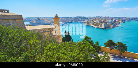 Il verde degli alberi di Herbert Giardini Ganado nascondere il massiccio muro di San Pietro e Paolo counterguard, affacciato sul Porto Grande di La Valletta con medievale Foto Stock