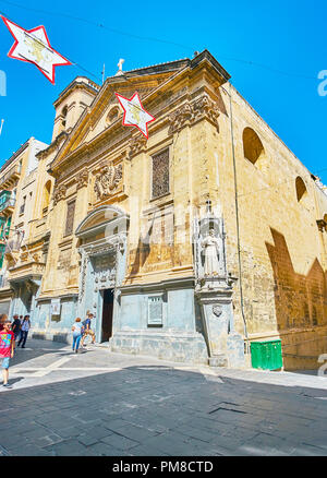 La Valletta, Malta - 17 giugno 2018: la facciata della chiesa di San Francesco di Assisi con pietra intagliata ghirlande e la scultura di San Francesco su buildi Foto Stock