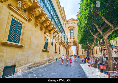 La Valletta, Malta - 17 giugno 2018: vecchio teatro di strada con una vista sulla parete laterale del Gran Maestro's Palace, decorate con pietra intagliata dettagli e la Pala Foto Stock