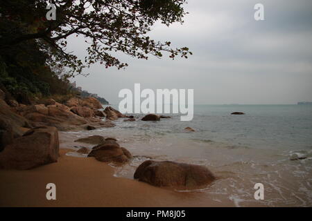 Deserta spiaggia rocciosa sul giorno nuvoloso Foto Stock