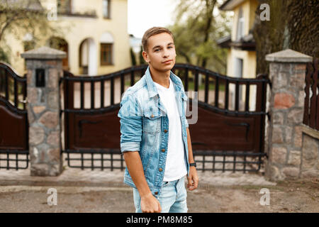 Elegante giovane ragazzo in jeans abiti vintage nei pressi di una recinzione di legno Foto Stock