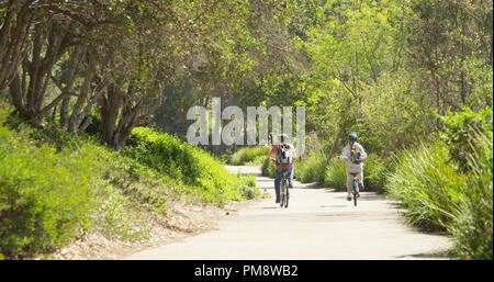 Attivo coppia caucasica equitazione biciclette presso un parco Foto Stock
