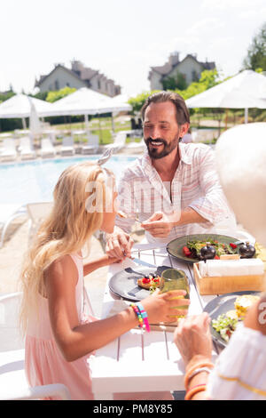 Nice positivo uomo gioioso alimentazione di sua figlia Foto Stock