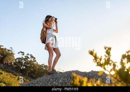 Escursionista femmina a scattare foto con la fotocamera digitale dalla cima di una collina. Giovane donna di catturare le immagini del bellissimo paesaggio. Foto Stock