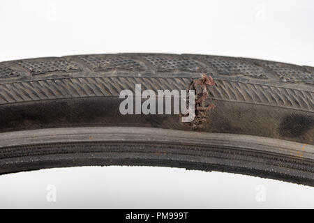 Un battuto pneumatico per bicicletta in officina. Una ruota di bicicletta forato con un chiodo. Sfondo chiaro. Foto Stock