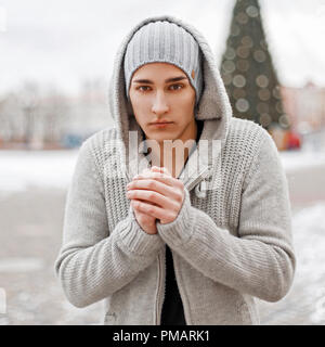 Il congelamento giovane uomo in inverno felpa lavorata a maglia su un sfondo innevato Foto Stock