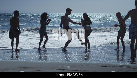 Silhouette di gruppo di multi etnico amici giocando a pallavolo sulla spiaggia Foto Stock