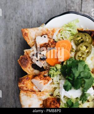 Il Tex-Mex incontra la cucina raffinata con piatti tradizionali texmex, tra cui tamales, talpa, quesadilla e nachos su un tavolo rustico con guarnizioni fresche. Foto Stock