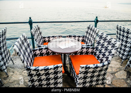Svuotare waterfront cafe e i tavoli e le sedie in Opatija, Croazia Foto Stock