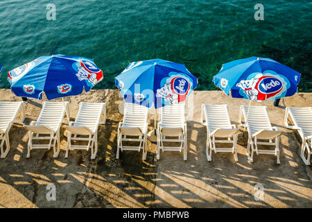 Vuoto bianco sole sedia sdraio e ombrelloni a bordo delle acque in Opatija, Croazia, che si affaccia sul Mare Adriatico Foto Stock