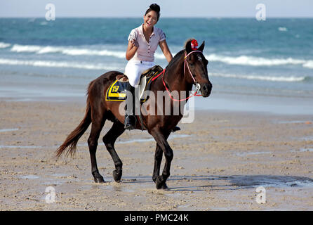 Donna equitazione spiaggia. Femmina ad un dressage di cavallo e ad un evento di moda equestre sulla spiaggia di Hua Hin Thailandia Foto Stock