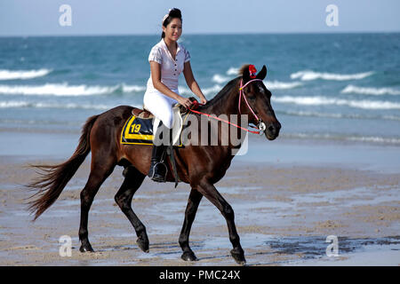 Donna equitazione spiaggia. Femmina ad un dressage di cavallo e ad un evento di moda equestre sulla spiaggia di Hua Hin Thailandia Foto Stock