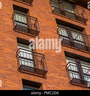 Elevato aumento strette con balconi e un muro di mattoni Foto Stock