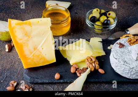 Diversi tipi di formaggi sulla scheda, formaggio piastra da un pezzo di formaggio duro, tagliata a fette sottili, rotondo blu testa di formaggio Foto Stock