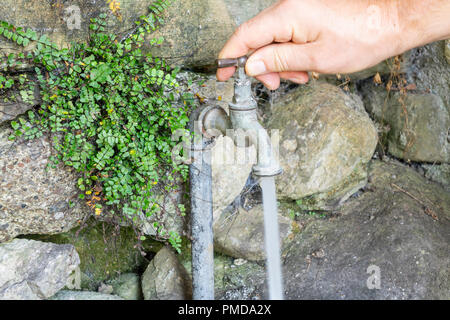 Un vecchio rubinetto su un muro di pietra Foto Stock