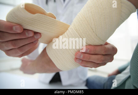 Ortopedico applicando un bendaggio sulla mano del paziente in clinica Foto Stock