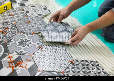 Pavimenti - uomo posa mattonelle esagonali sul pavimento Foto Stock