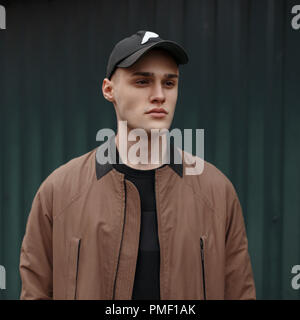 Ritratto di un giovane uomo in una moda elegante rivestire con un tappo sulla strada Foto Stock