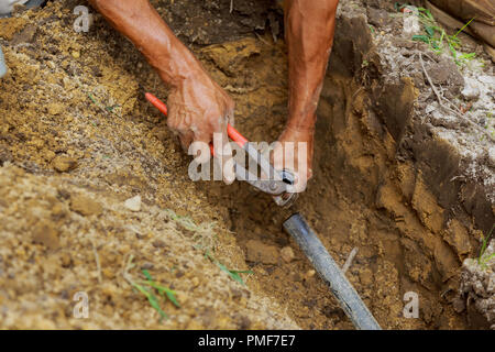 Installazione della metropolitana impianto sprinkler automatico per irrigare il giardino e prato uomo l'applicazione di primer di solvente e di cemento per tubi in PVC come parte Foto Stock