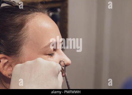 Una giovane donna ottenendo il suo naso forato Foto Stock