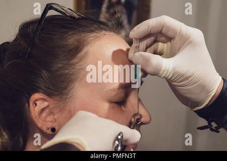 Una giovane donna ottenendo il suo naso forato Foto Stock