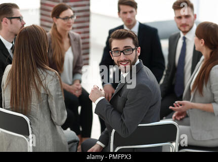 Giovane lavoratore seduto in un cerchio di colleghi Foto Stock