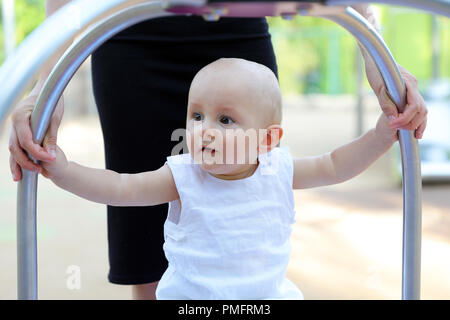 Carino dieci mesi Baby Boy giocare al parco giochi all'aperto. Vista ravvicinata Foto Stock