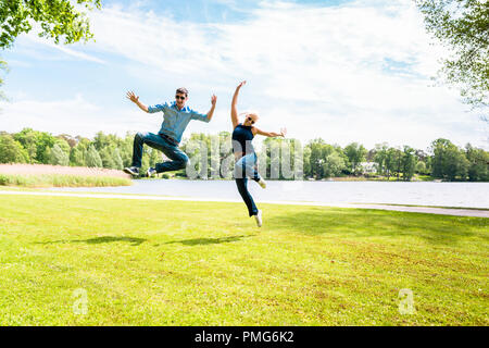 Emozionato coppia giovane jumping Foto Stock