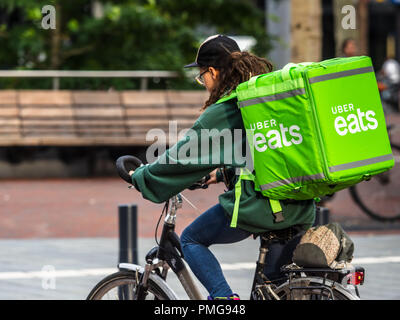 Uber mangia il cibo del corriere per la consegna di cicli in una piazza della città Foto Stock