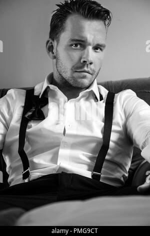 Uomo bello in hotel room, indossando smoking imprenditore con cravatta a farfalla allentati Foto Stock