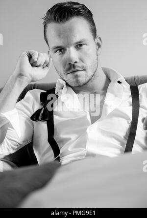 Uomo bello in hotel room, indossando smoking imprenditore con cravatta a farfalla allentati Foto Stock