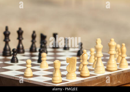 Chiudere fino a scacchi pezzi sul bordo, il fuoco selettivo sul cavaliere bianco. All'aperto gioco di scacchi in giornata soleggiata Foto Stock