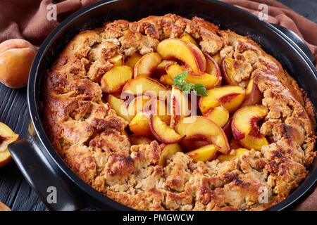 Cotta nel forno perfetto dessert meridionale Peach Cobbler in un nero teglia , close up, orizzontale Foto Stock