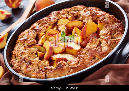 Peach Cobbler un profondo-piatto dessert di frutta, buono per la colazione cucinata in anticipo pasto, close up Foto Stock